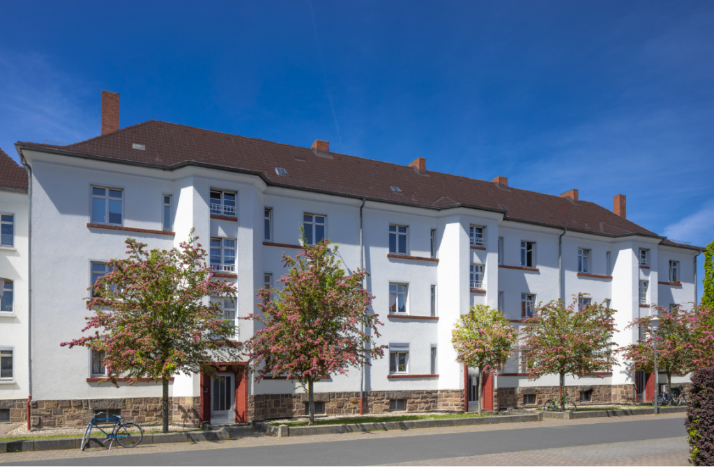 Das Foto zeigt ein Mehrfamilienhaus in Fulda. Die Eingänge werden von zwei blühenden Bäumen beschattet.