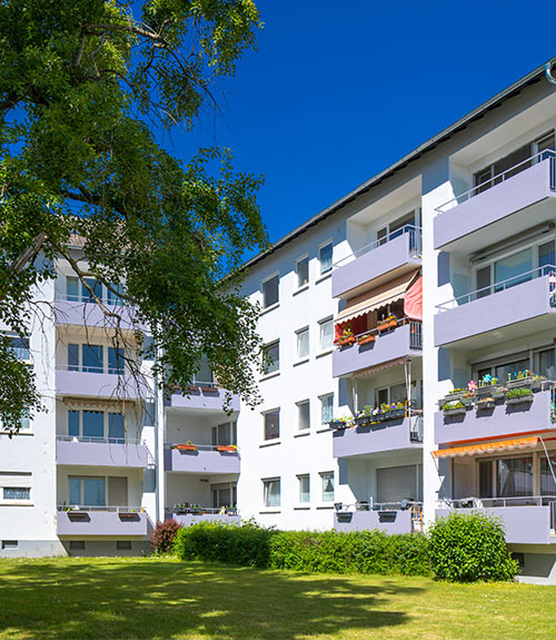 Das Foto zeigt ein Mehrfamilienhaus in Hattersheim. Jede Etage besitzt einen Balkon. Am Haus liegt eine große Grünfläche.