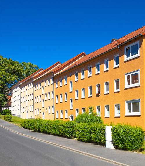 Das Foto zeigt in Reihen gebaute Mehrfamilienhäuser in Gelb und Weiß.